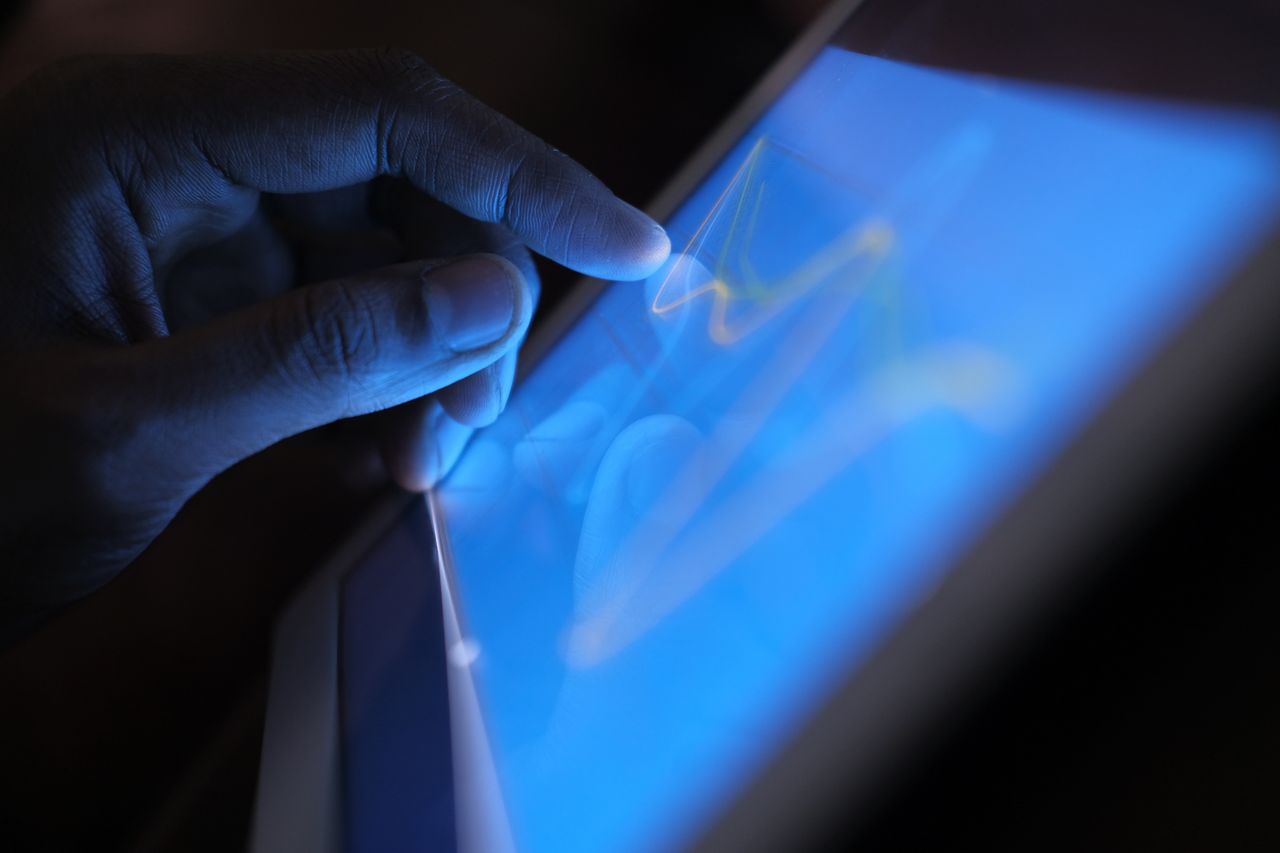 Close-up of a hand interacting with a touch screen tablet, showcasing modern technology use.